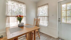 A dining area with a wooden table, two chairs, and a vase of flowers. - Weeki Wachee Home w/ Fire Pit: 13 Mi to Ocean! (Brooksville)