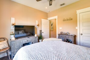 A bedroom with a large bed, a dresser, a television, and a door.