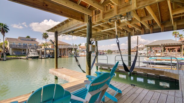 A wooden deck with chairs and a view of a marina with boats.