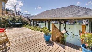 A wooden deck with a view of a marina, a hammock, and potted plants.