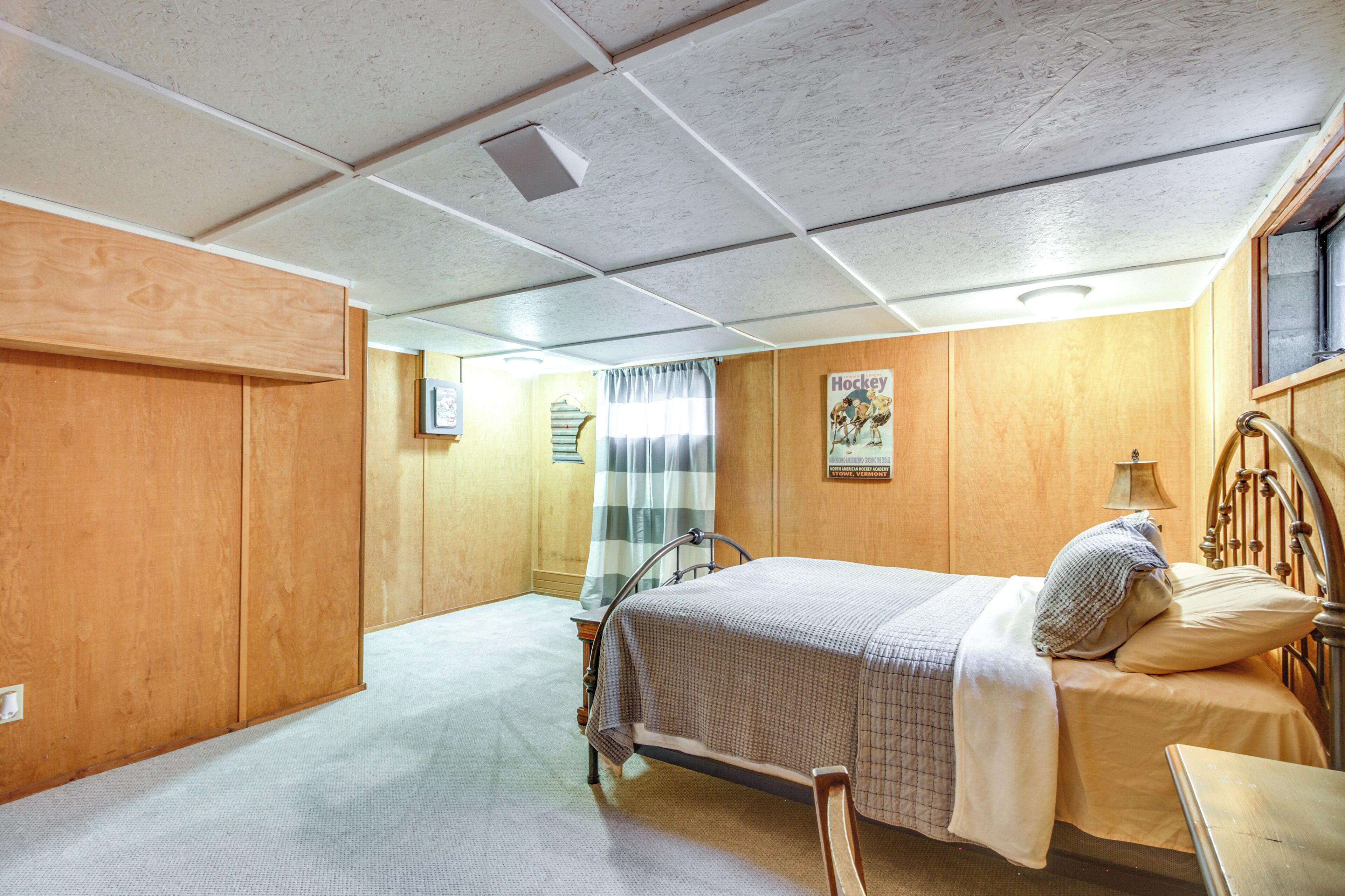 A bedroom with a bed, a bedside table, and a window with curtains.