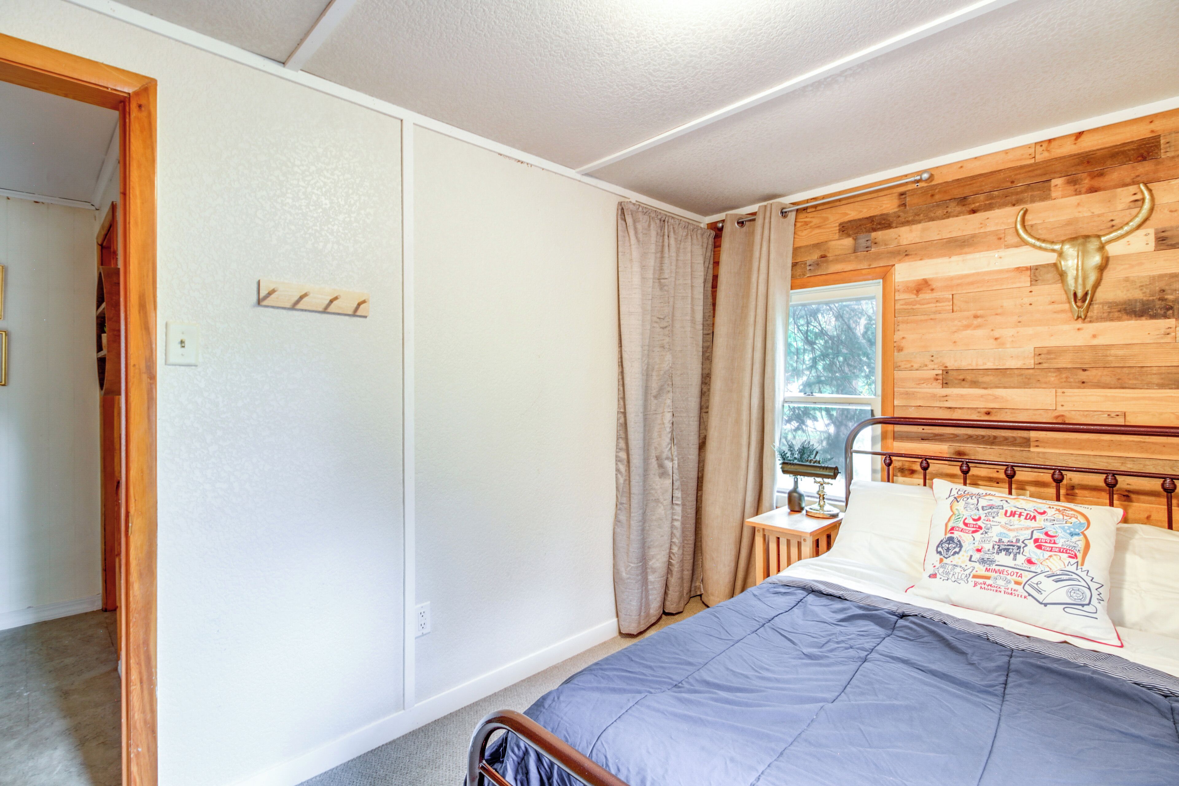 A bedroom with a bed, wooden headboard, and a window with curtains.