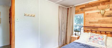 A bedroom with a bed, wooden headboard, and a window with curtains.