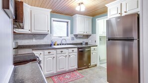 A kitchen with white cabinets, stainless steel appliances, a window, and a wooden ceiling. - Pet-friendly Pequot Lakes Vacation Rental Cabin! (Pequot Lakes)