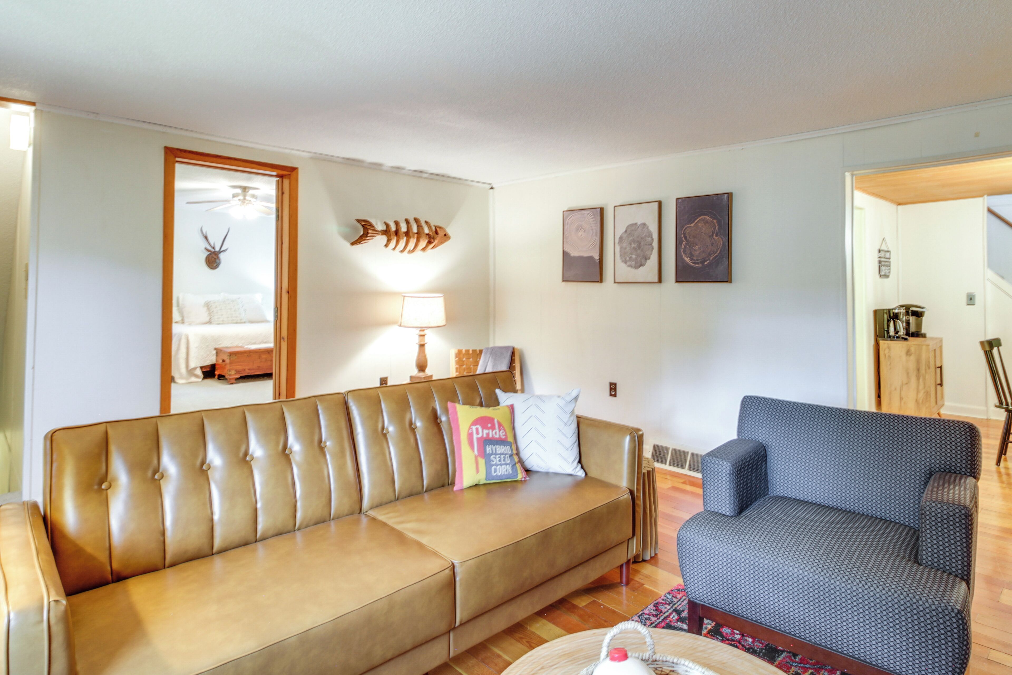 A living room with a brown leather sofa, a blue patterned armchair, a lamp, and wall art.