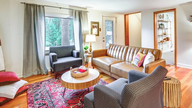 A living room with a leather sofa, two armchairs, a coffee table, and a rug. - Pet-friendly Pequot Lakes Vacation Rental Cabin! (Pequot Lakes)
