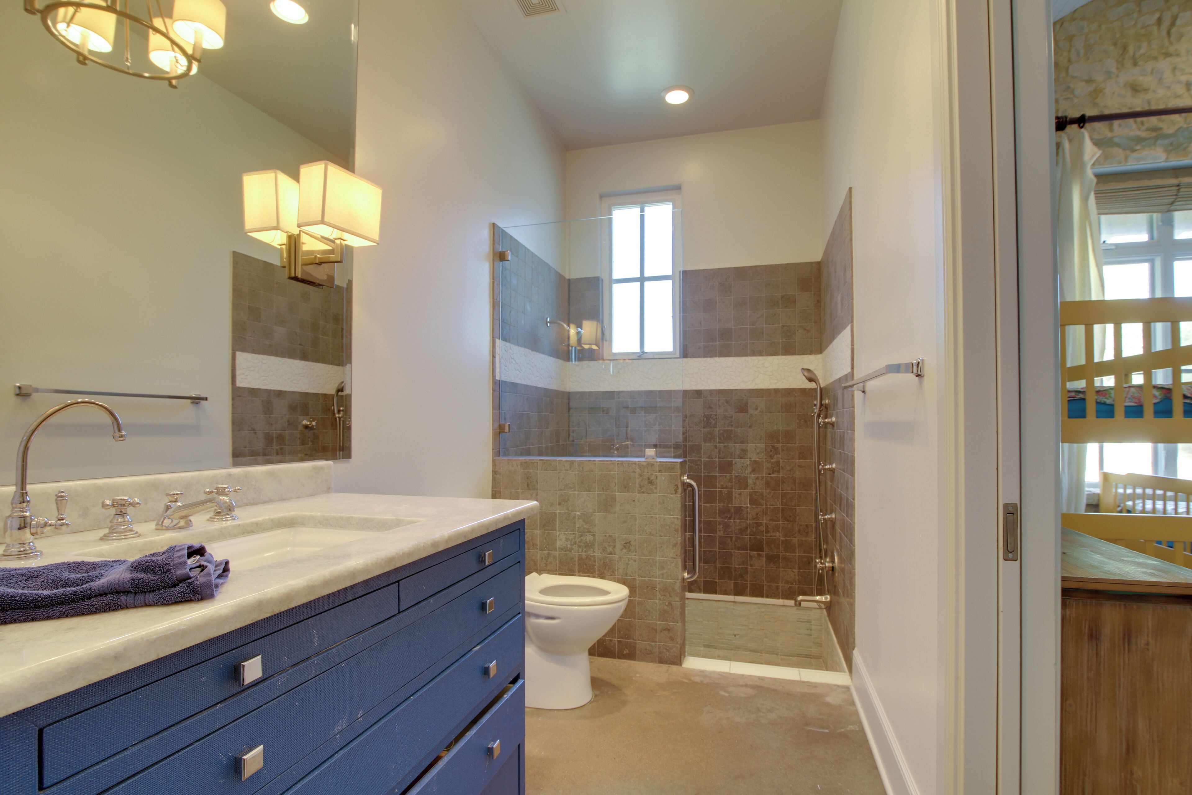 A modern bathroom with a glass-enclosed shower, a large mirror, and a vanity with a sink and towel.