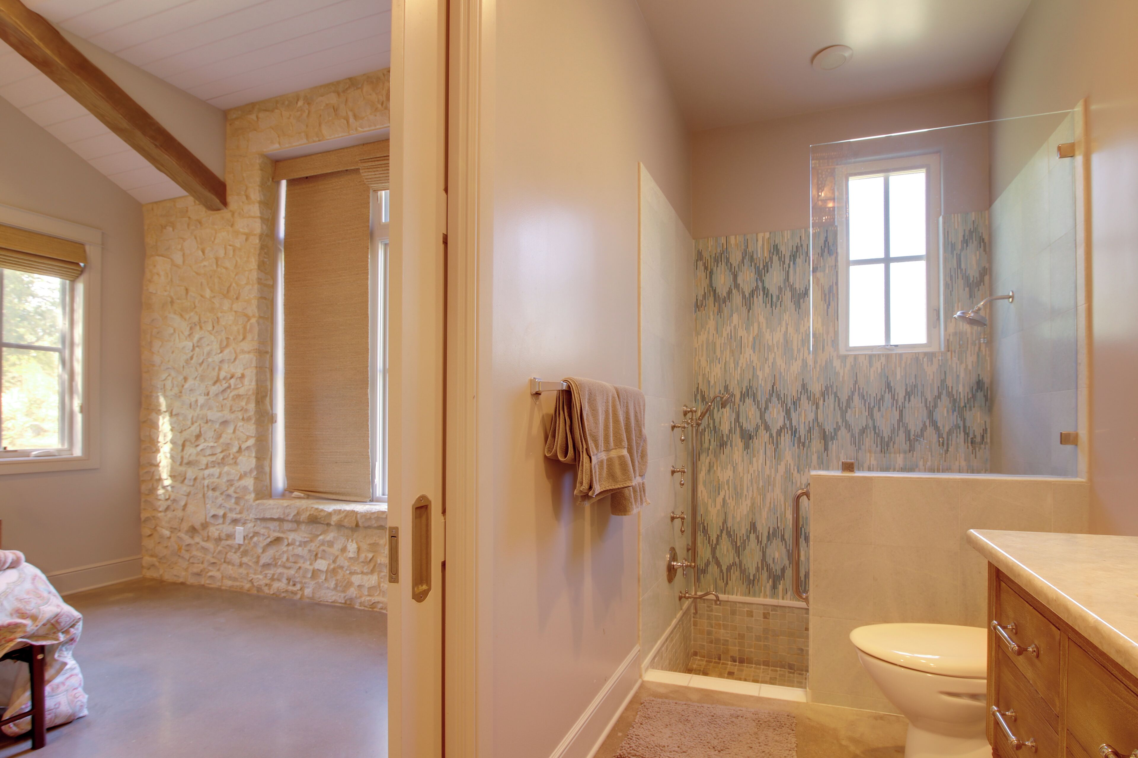 Une salle de bain avec un mur en pierre, une baignoire, des toilettes et un meuble-lavabo.