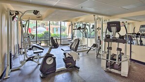 Un gimnasio con máquinas de cardio, equipo de levantamiento de pesas y un espejo grande.