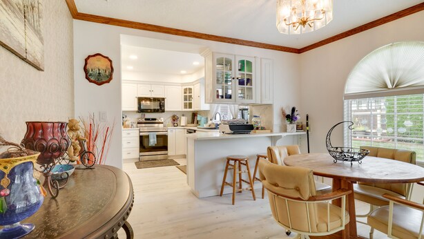 Una cocina moderna con armarios blancos, una isla central y una zona de comedor con una mesa redonda y sillas.