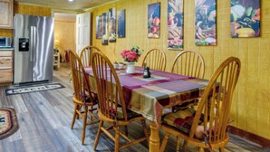 A dining area with a wooden table, chairs, and a refrigerator. - Fire Pit & Covered Deck! Cozy, Rustic Cosby Cabin (Cosby)