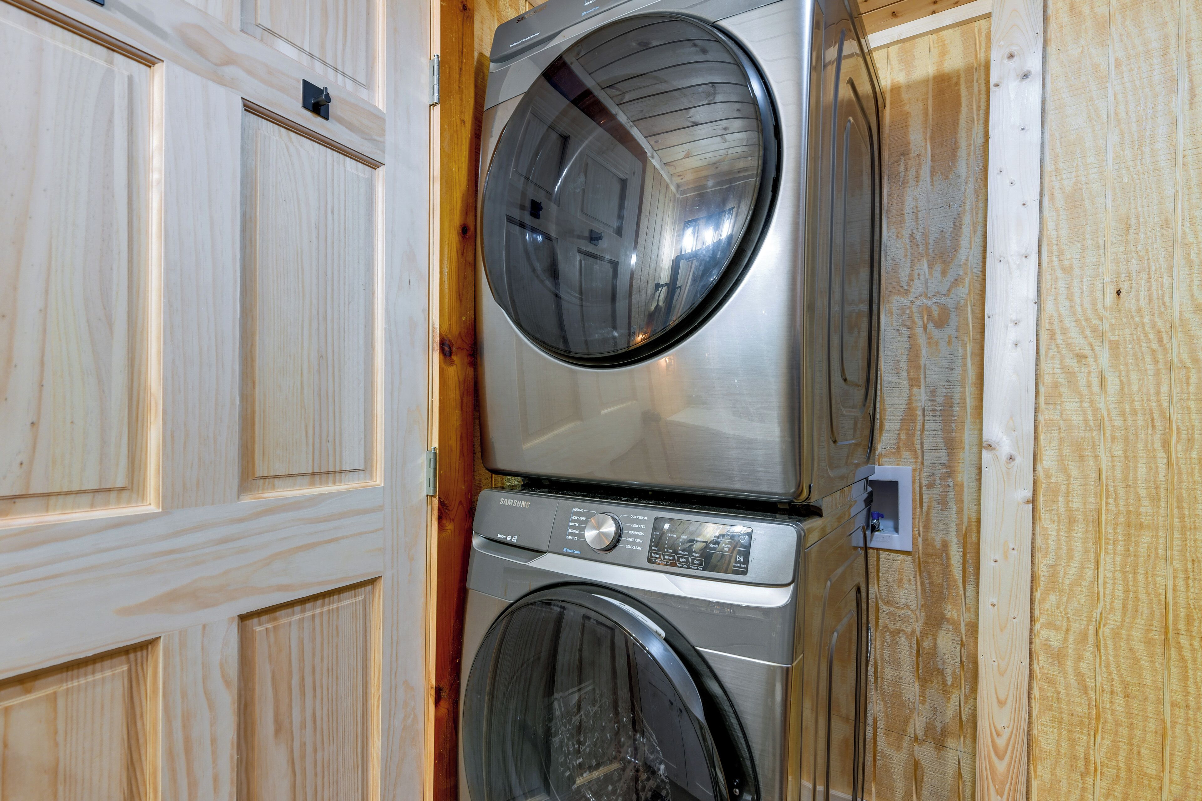 A stacked washer and dryer unit in a wooden utility room.