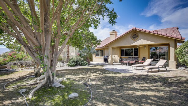 A house with a patio, outdoor seating, and a large tree. - Resort Perks, Patio & Gas Grill: Indio Retreat! (Indio)