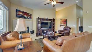 A living room with a sofa, coffee table, TV, and ceiling fan. - Resort Perks, Patio & Gas Grill: Indio Retreat! (Indio)