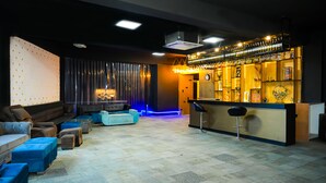 A modern bar area with a counter, bar stools, and a variety of glassware displayed on shelves. - HITE Resort Greater Noida (Greater Noida)