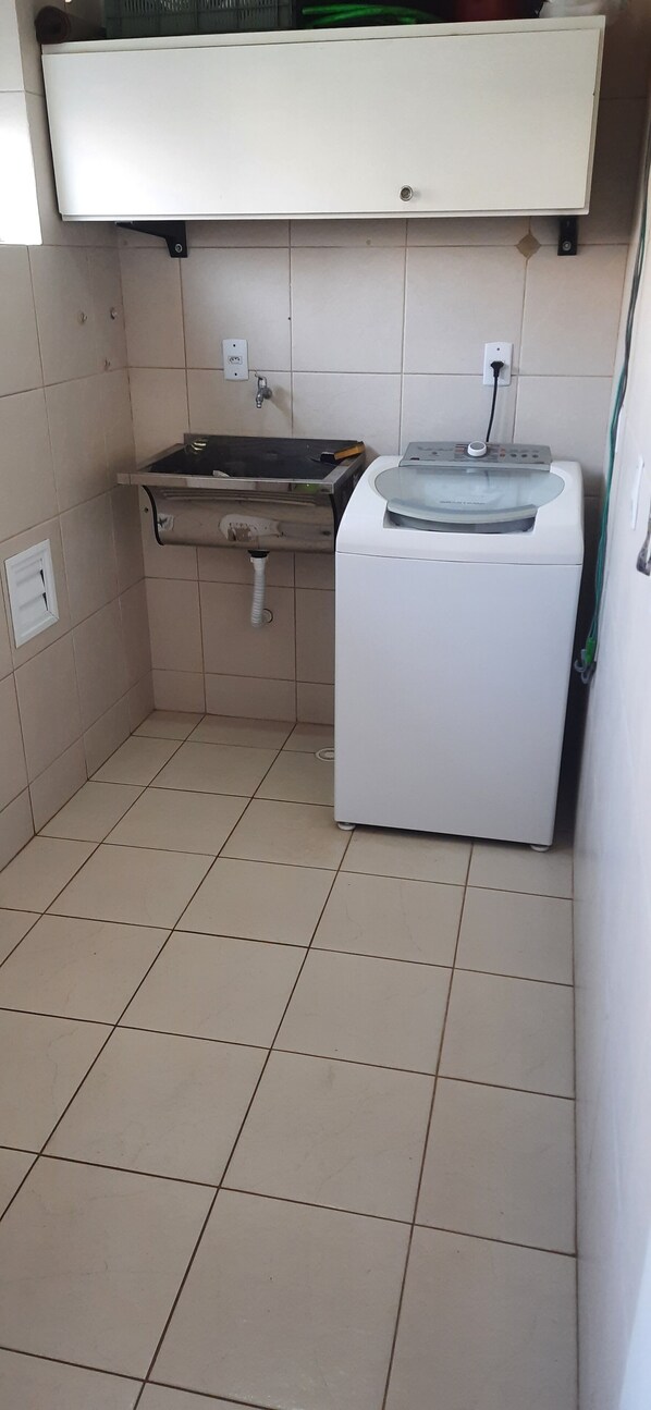 Une petite cuisine équipée d’un évier, d’un lave-linge et d’un placard au-dessus de l’évier.