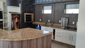 Une cuisine moderne dotée de plans de travail en granit, d’une cuisinière encastrée et d’un meuble à vin.
