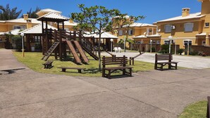 Une aire de jeux avec des toboggans et des structures d’escalade, entourée de bancs et bordée d’un chemin pavé.