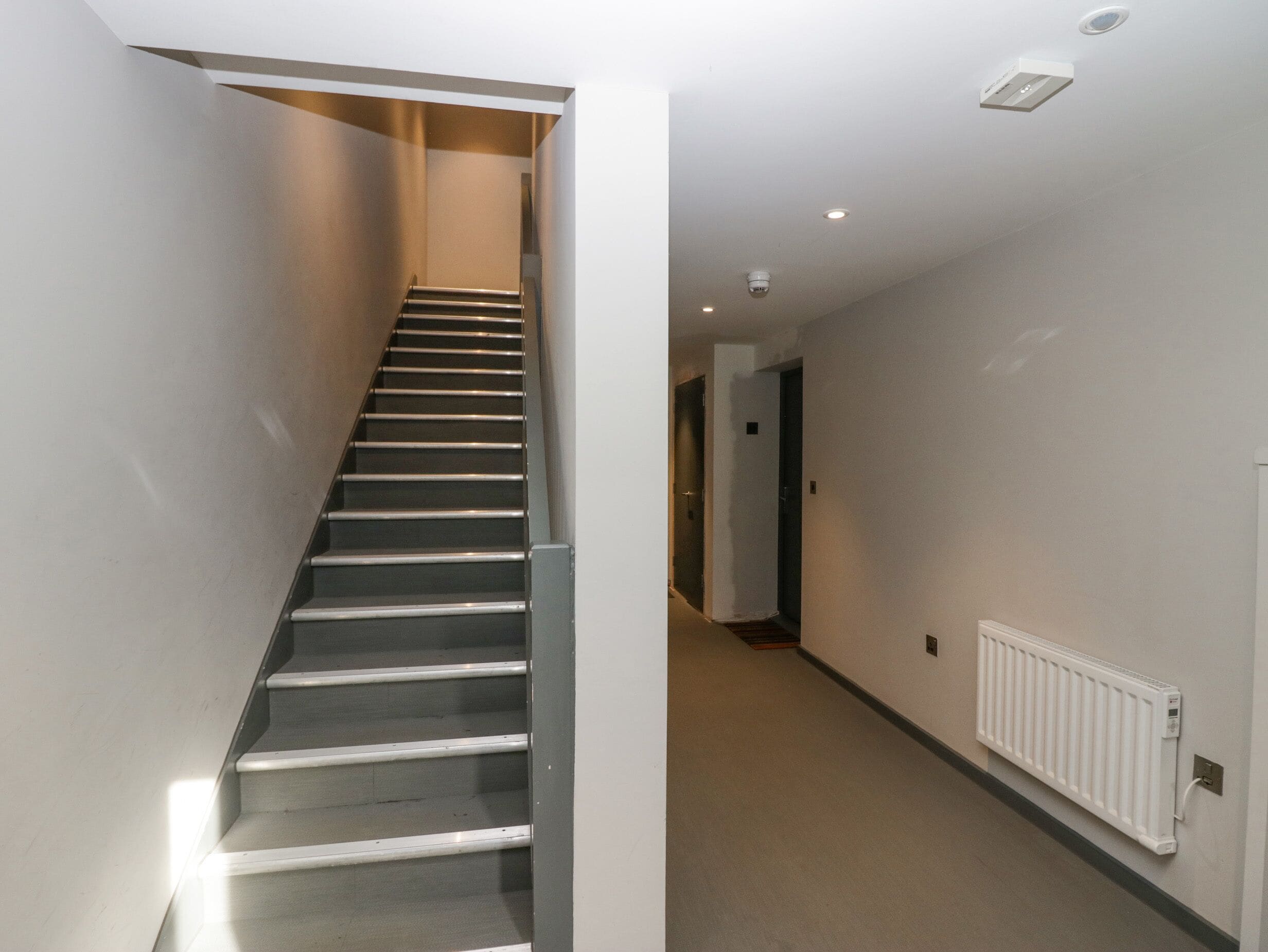 A staircase leading to a landing with a white radiator on the wall.