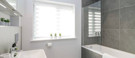 A modern bathroom with a large window, a bathtub, and a shower area.