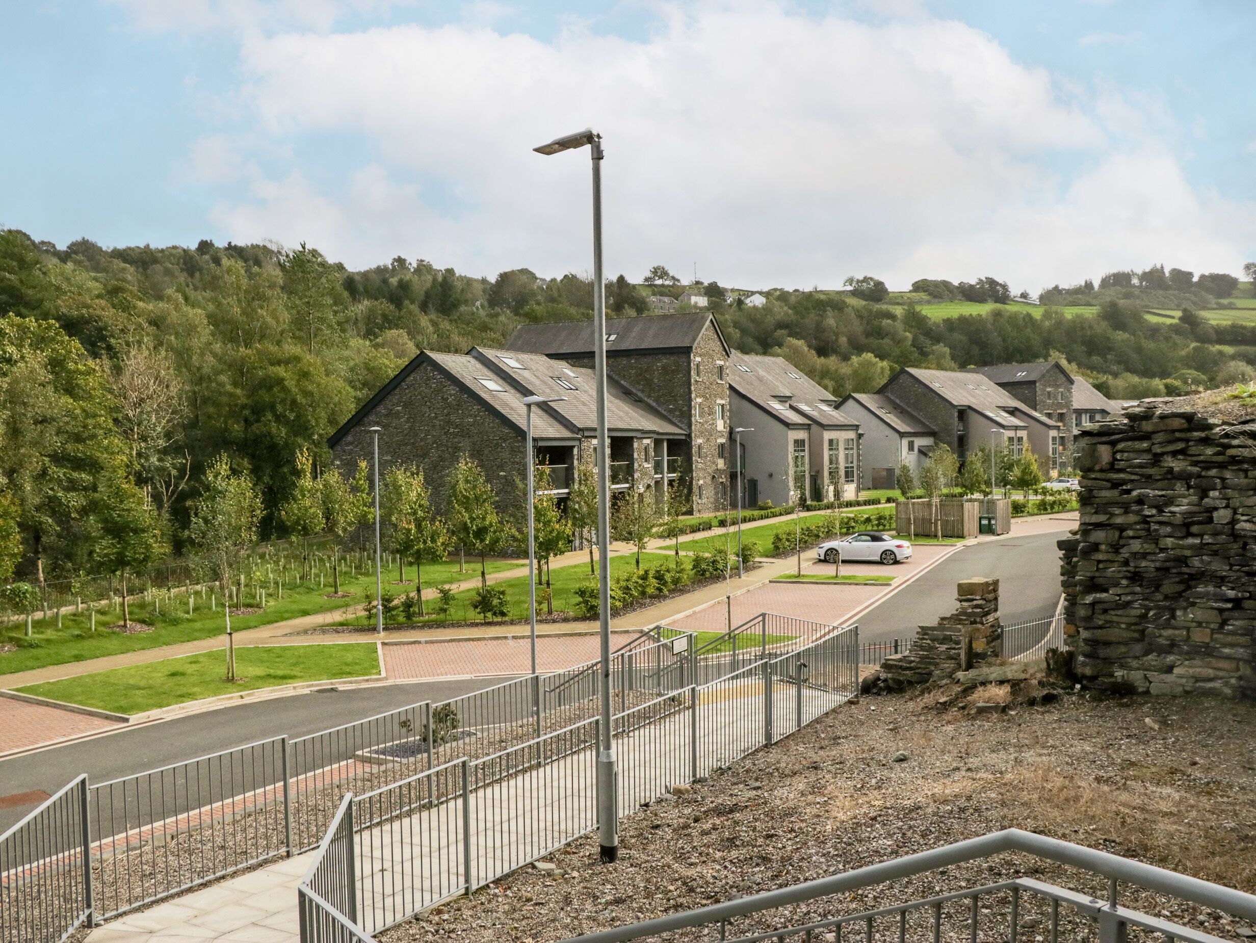 Un quartier résidentiel avec des maisons modernes, une route asphaltée et un mur en pierre.