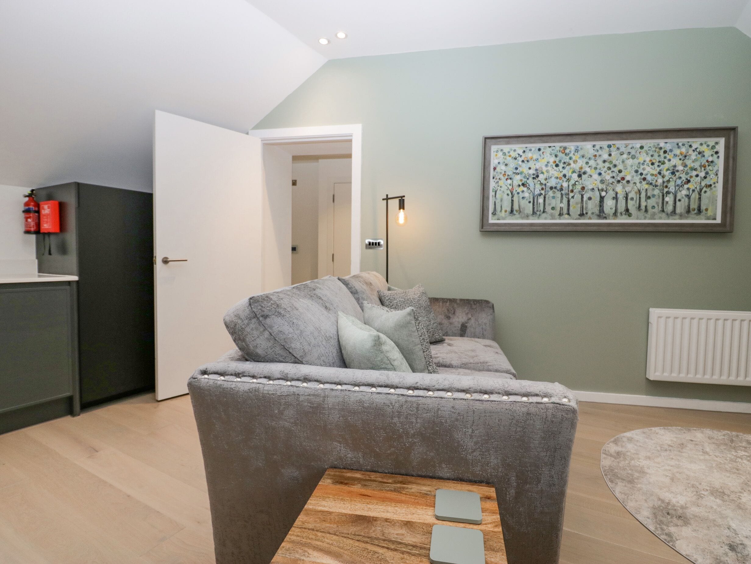 A living room with a grey sofa, a wooden coffee table, a painting on the wall, and a radiator.