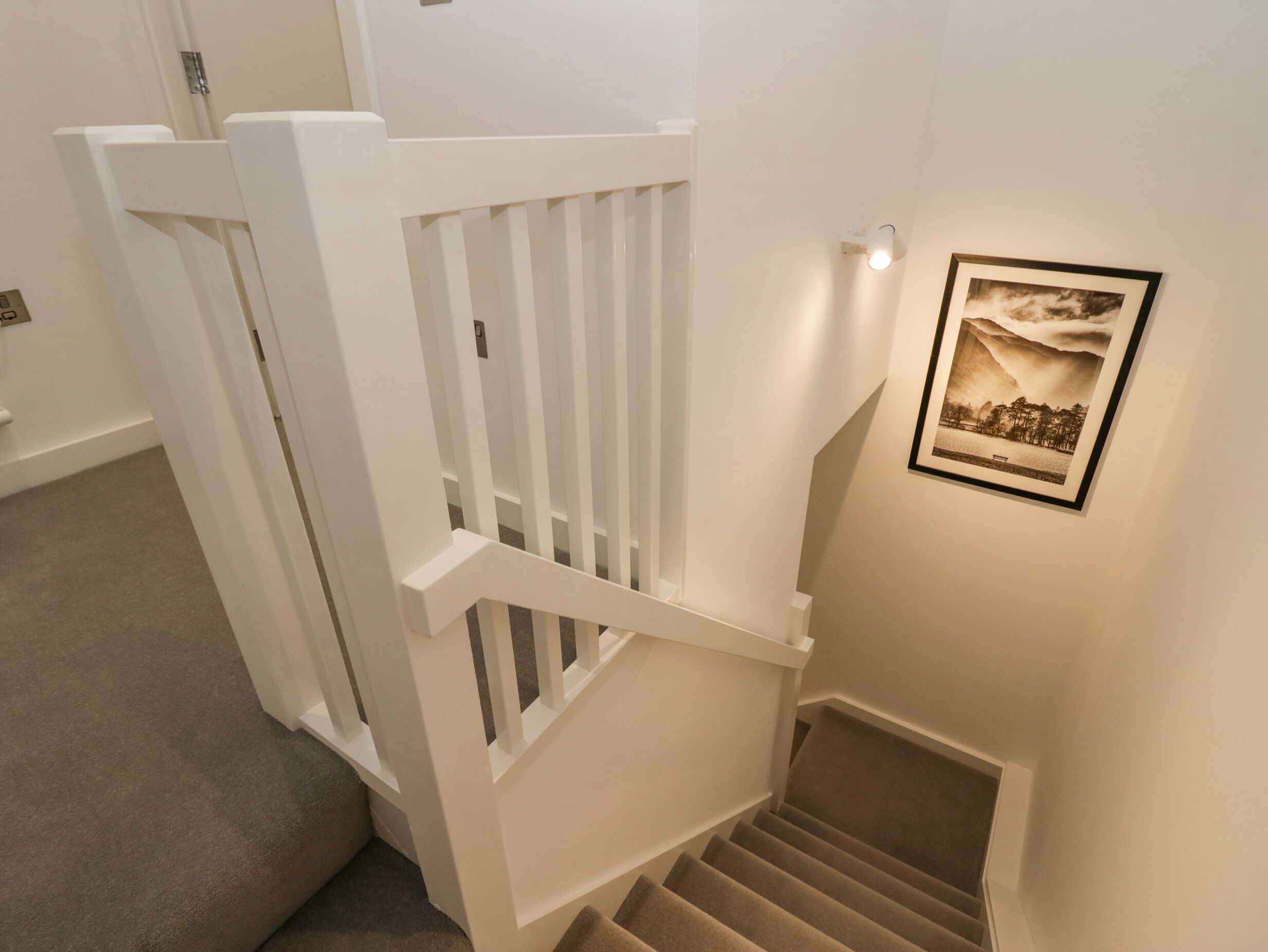 A staircase with white railings and a framed picture on the wall.
