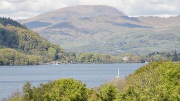 A lake surrounded by hills with a sailboat in the foreground.