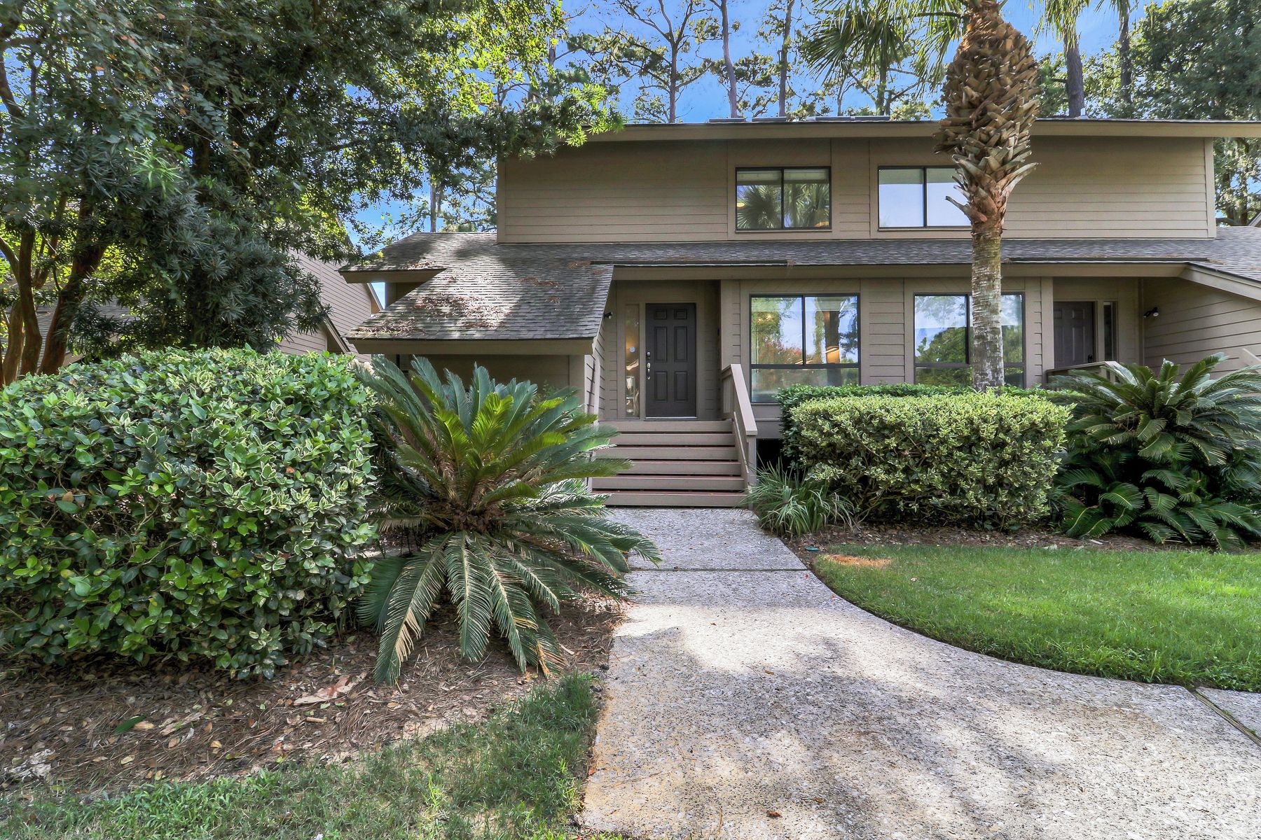 A two-story house with a front porch, a driveway, and well-maintained landscaping.