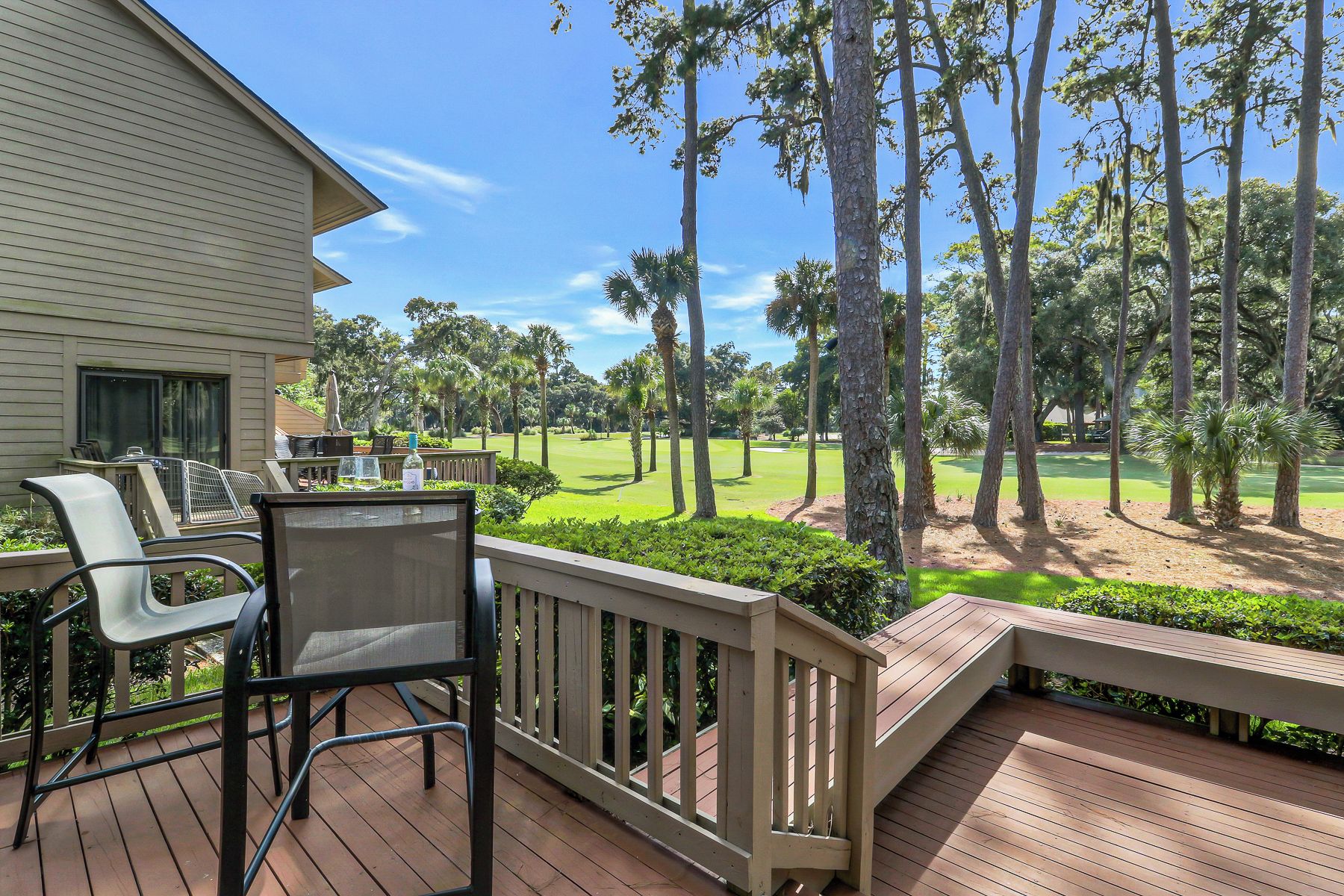 A deck with outdoor furniture overlooking a golf course.