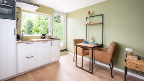A modern kitchen with white cabinets, a built-in oven, and a dining area with a table and chairs.