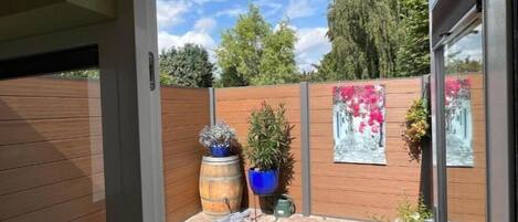 A patio area with a wooden fence, potted plants, and a brick floor.