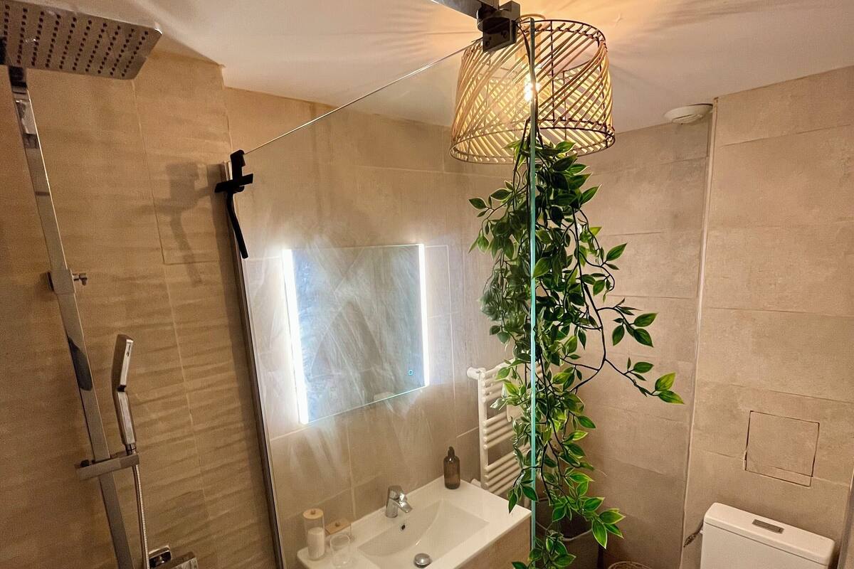 Moderni kylpyhuone, jossa on lasiseinällä varustettu suihku, pesuallas ja wc.