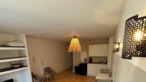 Un dormitorio con cama, televisión, escritorio y kitchenette.