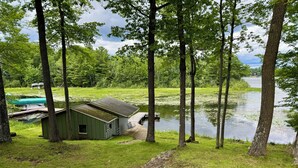 A lakeside cabin with a dock, surrounded by trees and grassy areas. - Minocqua Chain - SUMMER DATES AVAILABLE! (Minocqua)