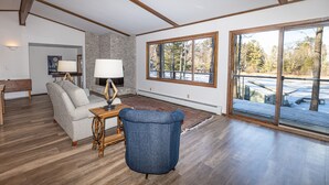 A spacious living room with a fireplace, large windows, and a view of the outdoors. - Minocqua Chain - SUMMER DATES AVAILABLE! (Minocqua)
