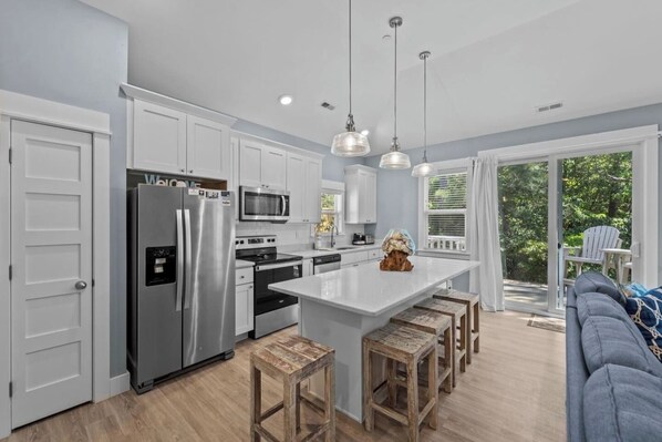 A modern kitchen with white cabinets, stainless steel appliances, and a central island with stools.