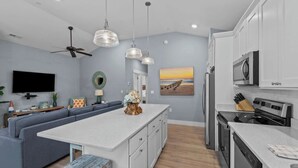 Una cocina moderna con armarios blancos, una isla central y un comedor con un sofá azul.