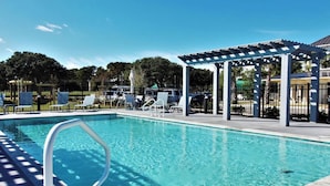 Una piscina con sillas de descanso y un área de estar techada.