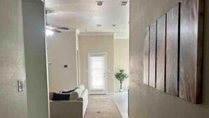 Un couloir doté d’un sol recouvert de moquette, d’un canapé blanc et d’une porte au fond.