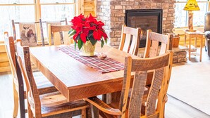 Une table de salle à manger en bois, avec des chaises, une cheminée et une couronne de Noël.
