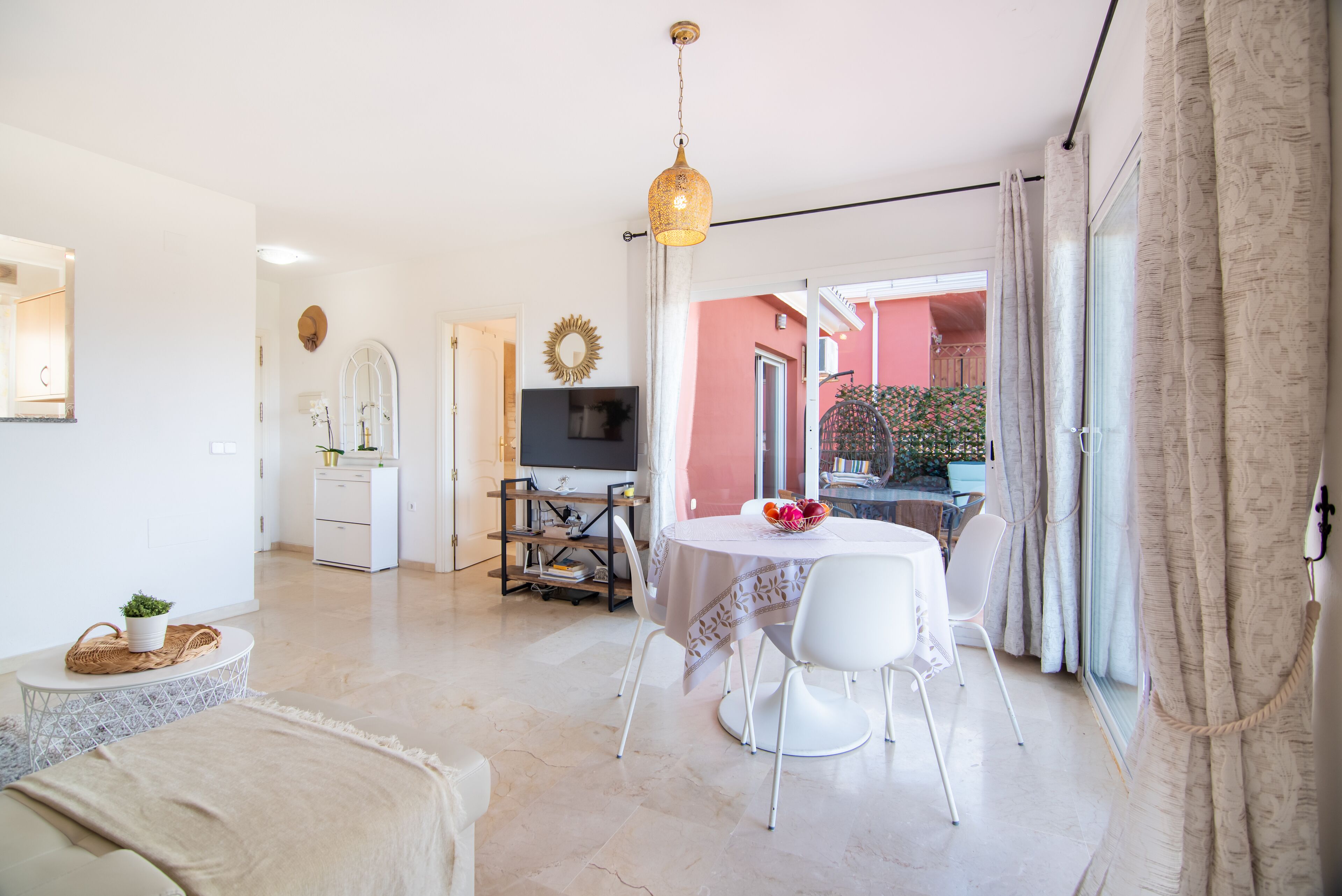 Una sala de estar luminosa con comedor, televisor y vistas al exterior.