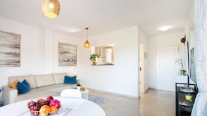 A modern living room with a sofa, a round table with a fruit bowl, and a hanging light fixture. - Spacious condo with Sea View, Walking distance to the Beach, Pool, Parking, Wifi (manilva)