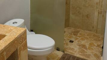 Un baño con inodoro, ducha con cerramiento de vidrio y una lámpara de techo circular.