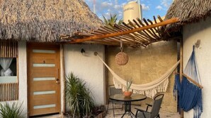 A thatched-roof outdoor area with a wooden door, a hammock, a table with chairs, and potted plants. - Casa con Habitación Doble, Casa Maya (Izamal)