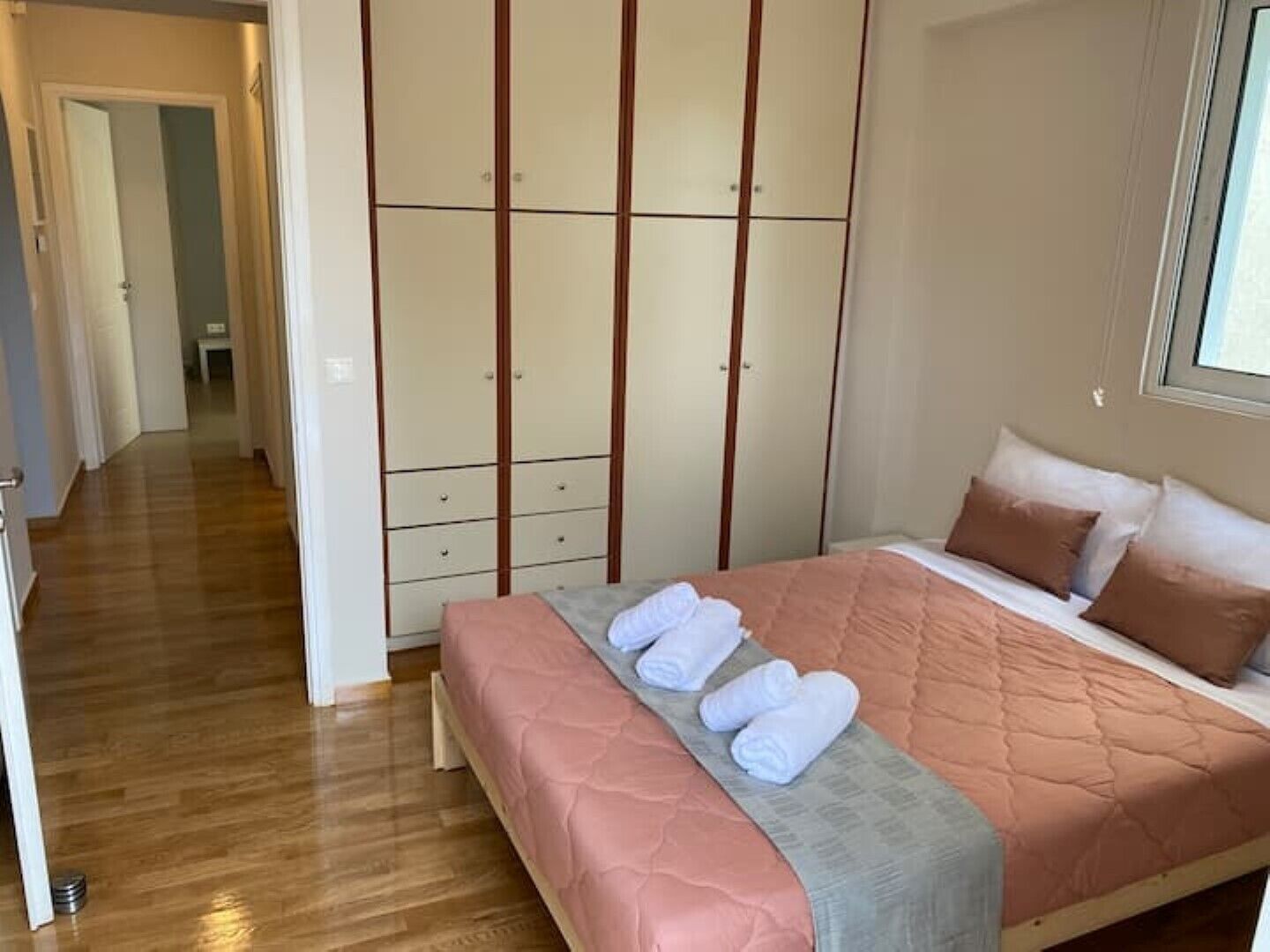 Um quarto com cama, guarda-roupa e corredor.