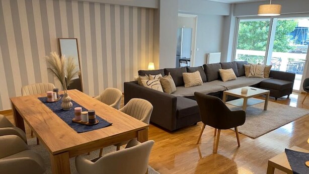 A modern living room with a wooden dining table, a sofa, and a coffee table. - Classy 3BR with 2 Bathrooms Apartment in Marousi (Athens)