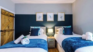 A hotel room with two beds, a wooden door, and three framed pictures on the wall. - NEW! Stylish home, amazing location, sleeps 6! (Chester)