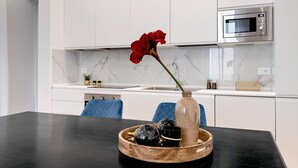A modern kitchen with white cabinets, a marble backsplash, and a black countertop. - Genteel Home Giraldi (Florence)