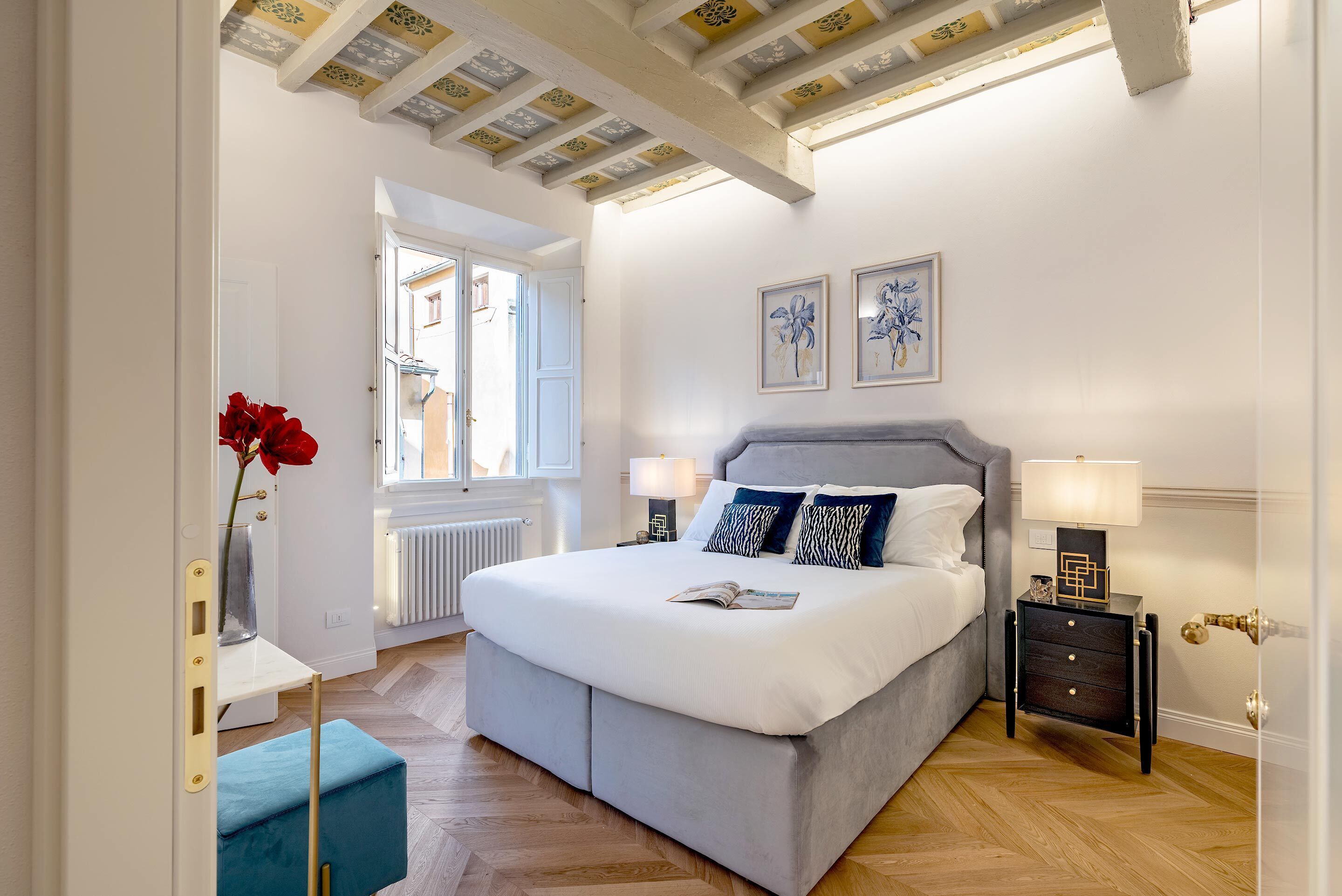 Um quarto com cama, mesas de cabeceira, um radiador e uma janela.
